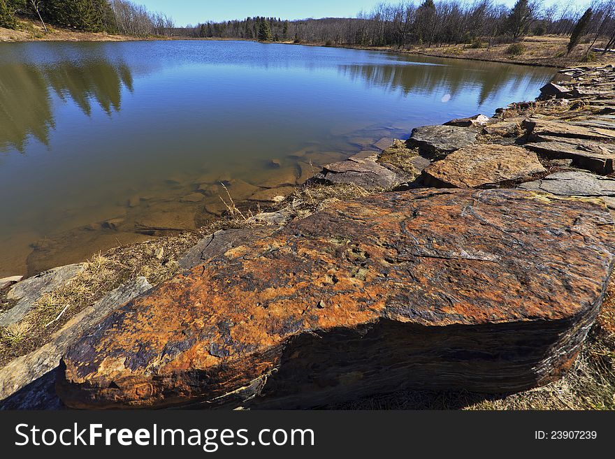 Mountain lake, old rocks and deep blue sky in early spring