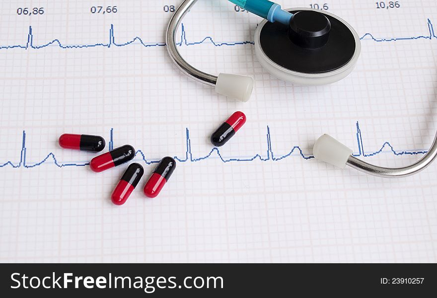 Stethoscope and pills on a printout of a heartrate graph. Stethoscope and pills on a printout of a heartrate graph