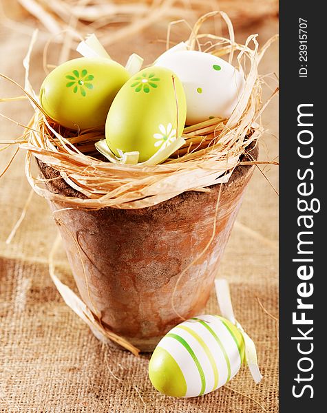 Easter eggs in straw filled pot on burlap background. Easter eggs in straw filled pot on burlap background