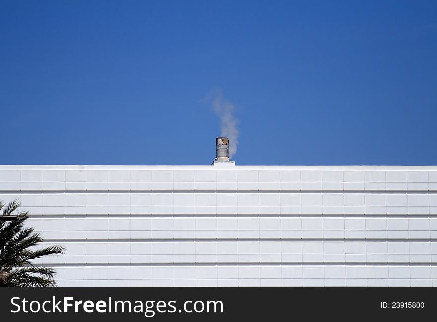 Small Smoke Stack Against A Blue  Sky