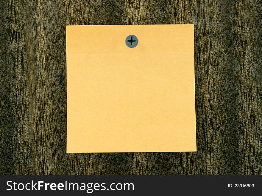 Yellow sticky note on the wooden background