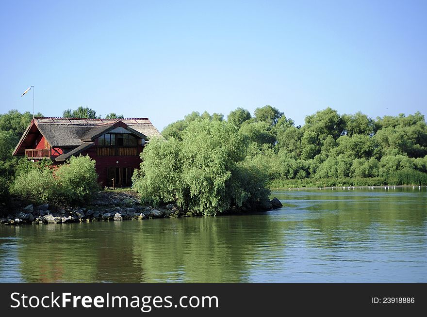 Red house among trees and along a river. Red house among trees and along a river.