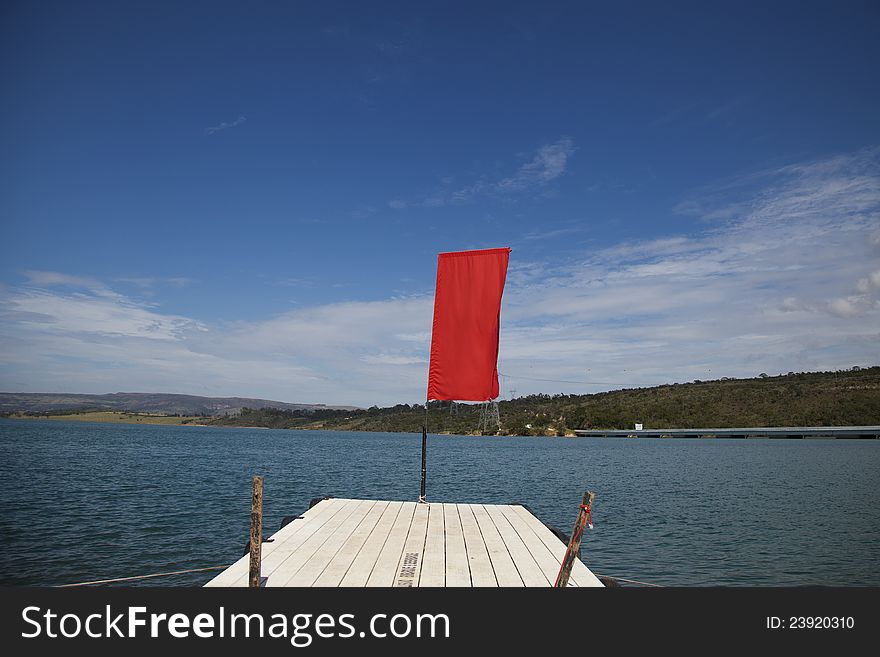 Wooden wharf / jetty over the blue water with red flag. Wooden wharf / jetty over the blue water with red flag