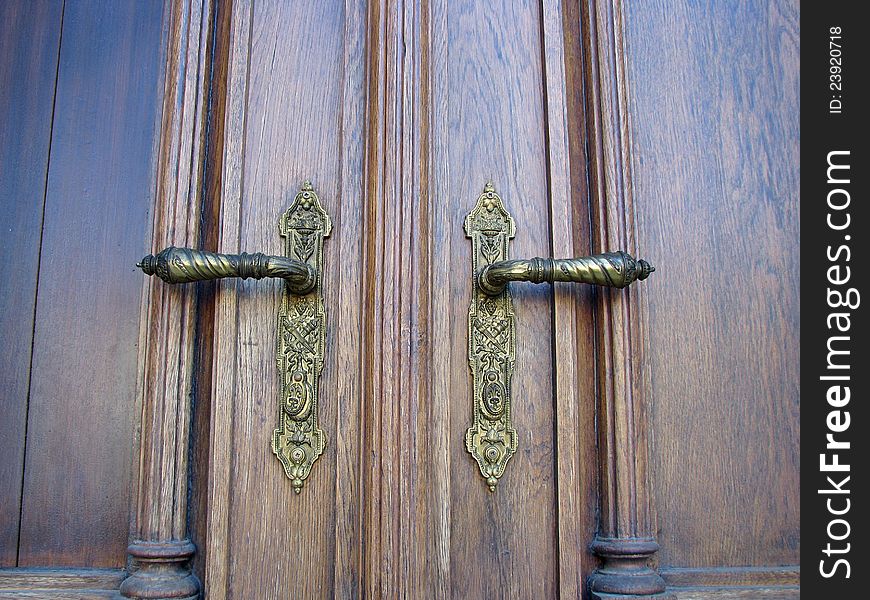 Ornamented front door handles on wooden door. Ornamented front door handles on wooden door