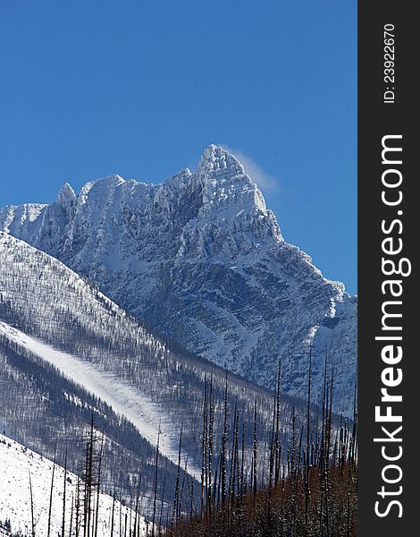 This image of the rugged mountain peak with the wind blowing snow off the summit was taken in Glacier National Park, MT. This image of the rugged mountain peak with the wind blowing snow off the summit was taken in Glacier National Park, MT.