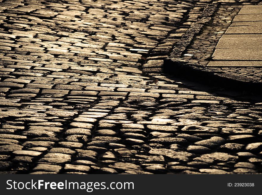 Rough texture of wet cobblestones, old side-street