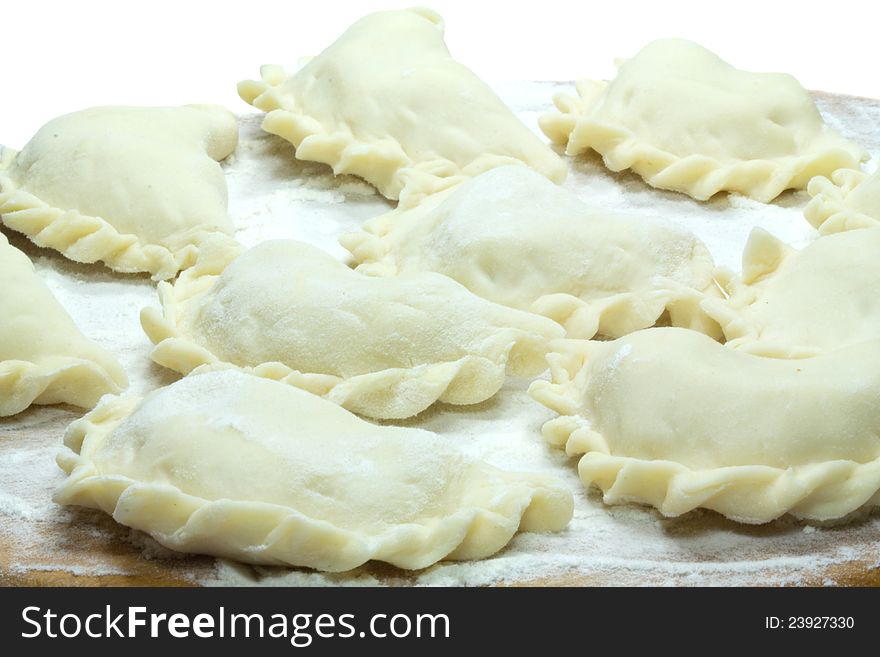 Home-made dumplings lay on a wooden board sprinkled with flour