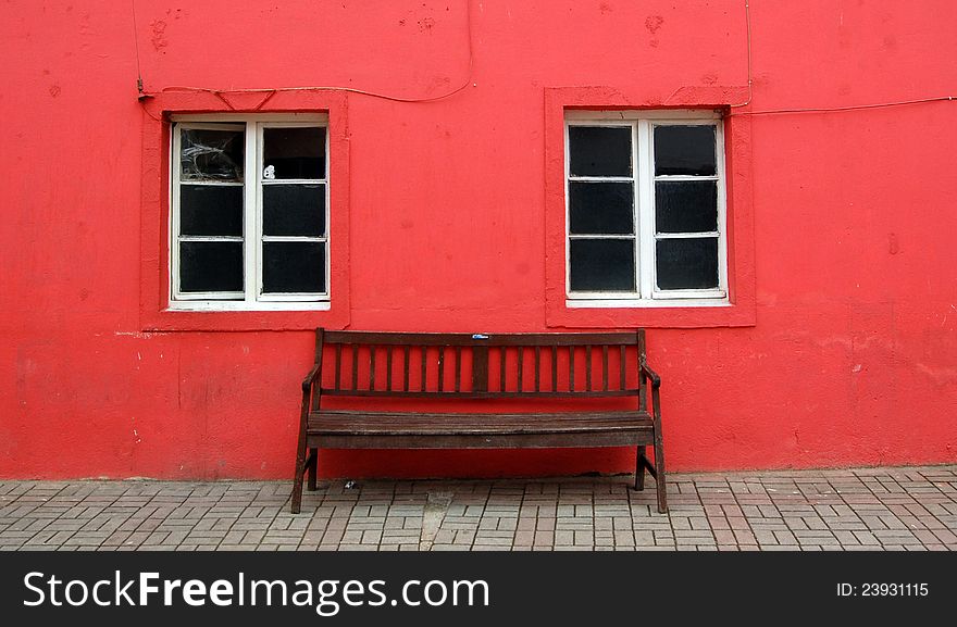 Bench And Two Windows On Red Wall