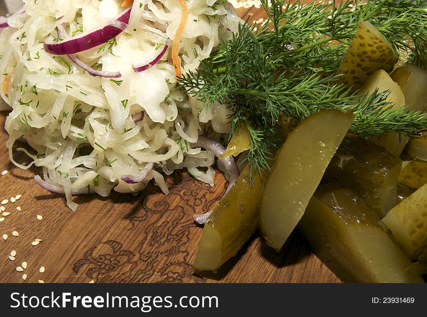 Pickled cabbage, cucumbers, onions on a wooden plate. Pickled cabbage, cucumbers, onions on a wooden plate