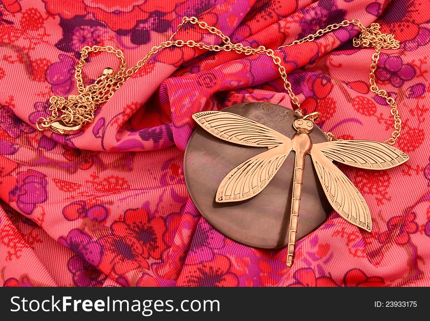 A dragonfly neckless on a red fabric
