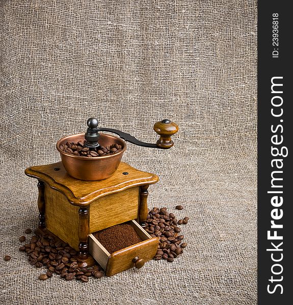 Coffee grinder with coffee beans on sackcloth background