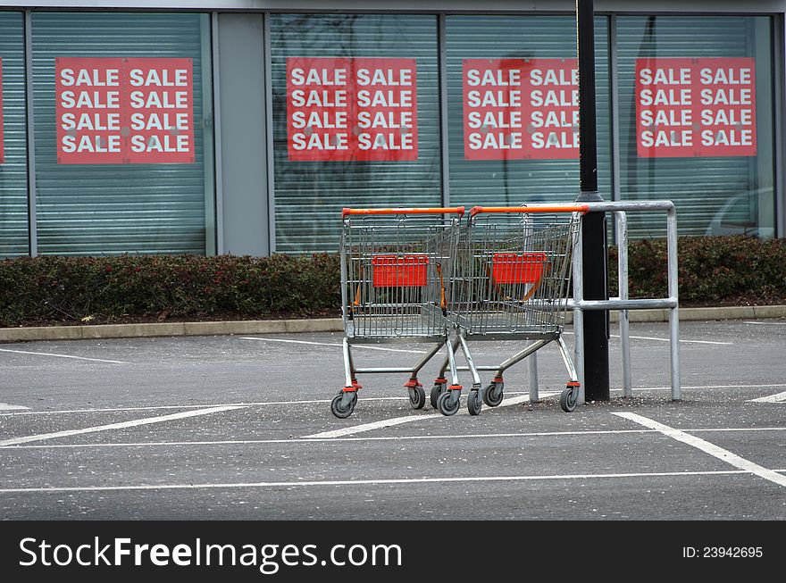 Shopping trollies in parking lot with sale in background