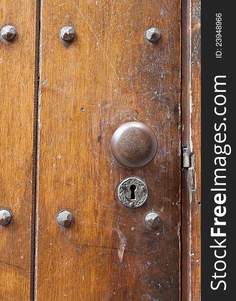 A very old door handle and lock on a vintage wooden building with craftsmanship and originality.