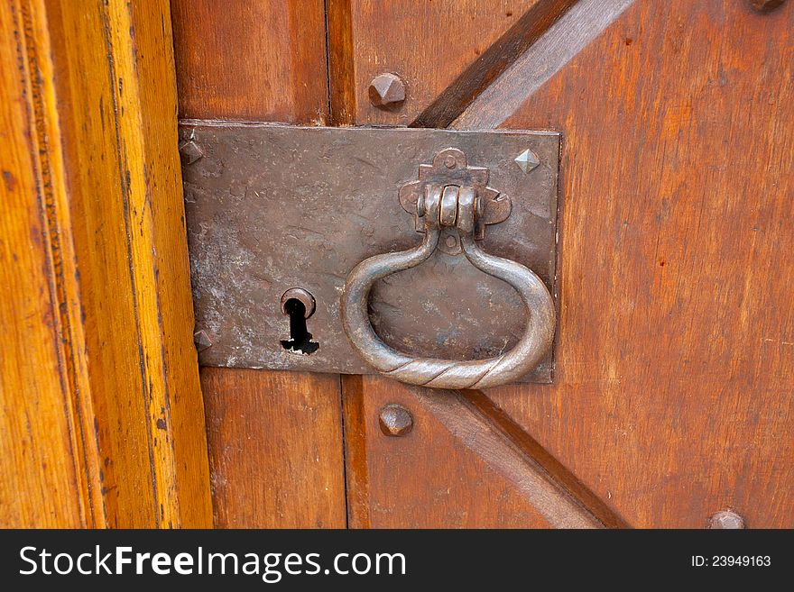 A very old door handle and lock on a vintage wooden building with craftsmanship and originality.