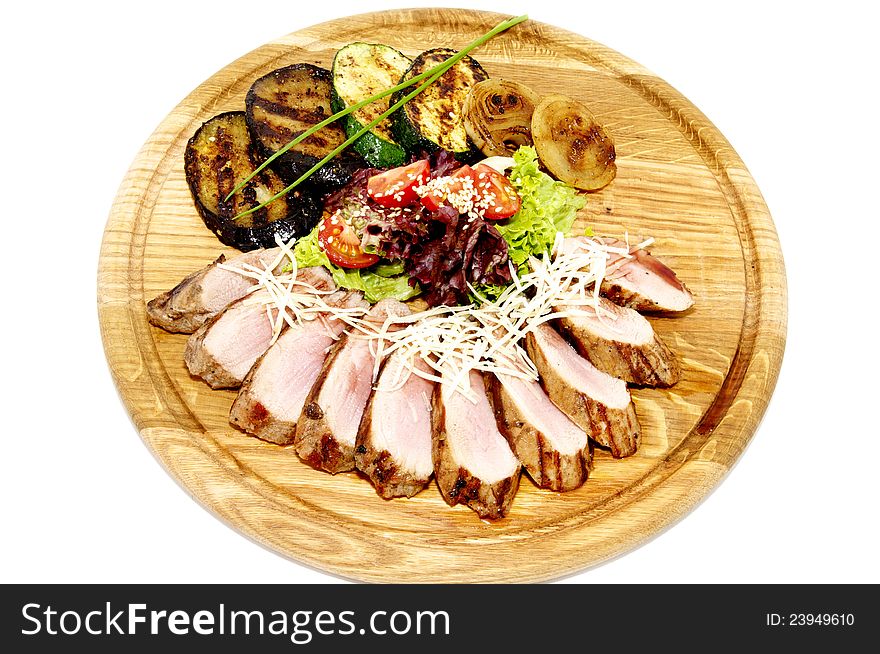 Grilled meat with vegetables and herbs on a wooden plate