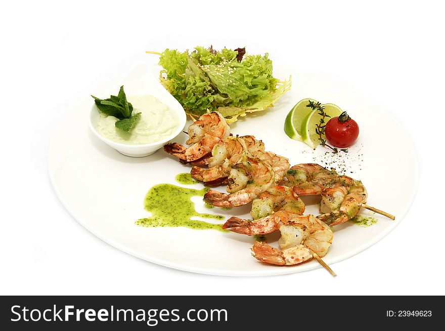 Skewers of shrimp on a white plate with vegetables and lemon