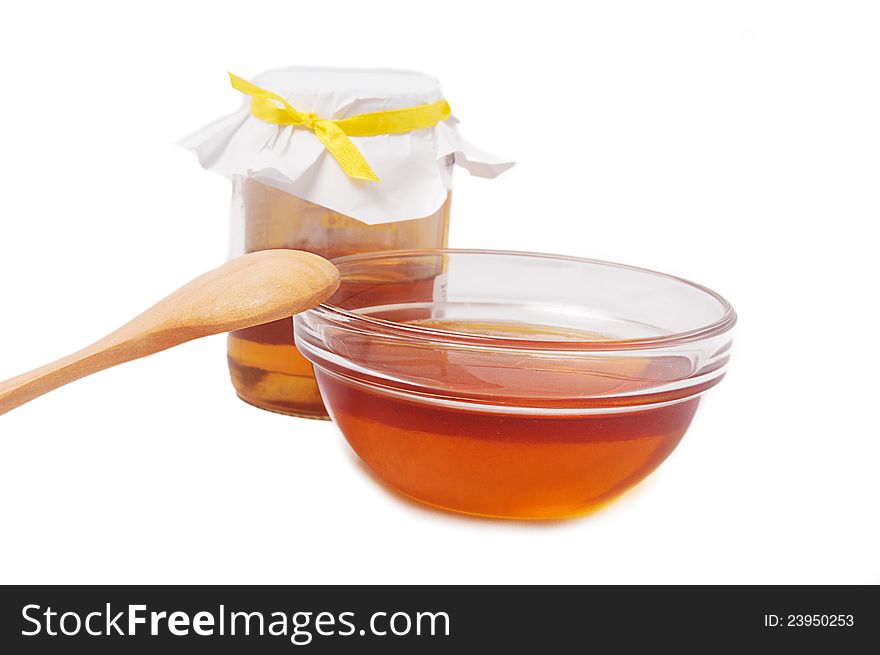 Honey jar with plate and wooden spoon over white