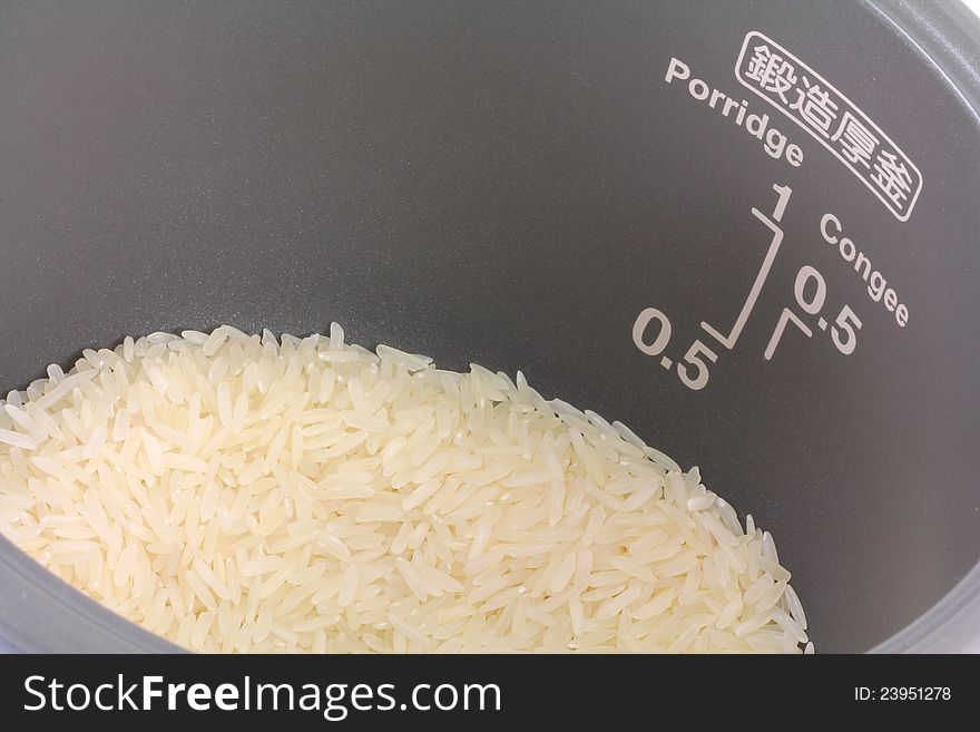 Closeup photo of Raw white Jasmine rice in electric non-stick rice cooker pot, ready to be cooked. Closeup photo of Raw white Jasmine rice in electric non-stick rice cooker pot, ready to be cooked