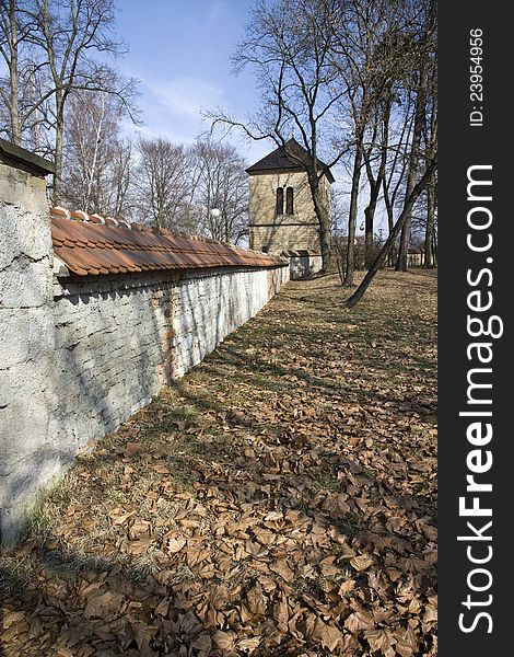 Brick fortification wall in the park, dry fallen leaves on the ground in the park, rychnov park in autumn, fortification wall and a park in sunny day, czech architecture. Brick fortification wall in the park, dry fallen leaves on the ground in the park, rychnov park in autumn, fortification wall and a park in sunny day, czech architecture