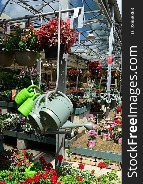 Flowers,shrubs,water cans and other garden supplies  on display in the garden section of a home improvement center. Flowers,shrubs,water cans and other garden supplies  on display in the garden section of a home improvement center