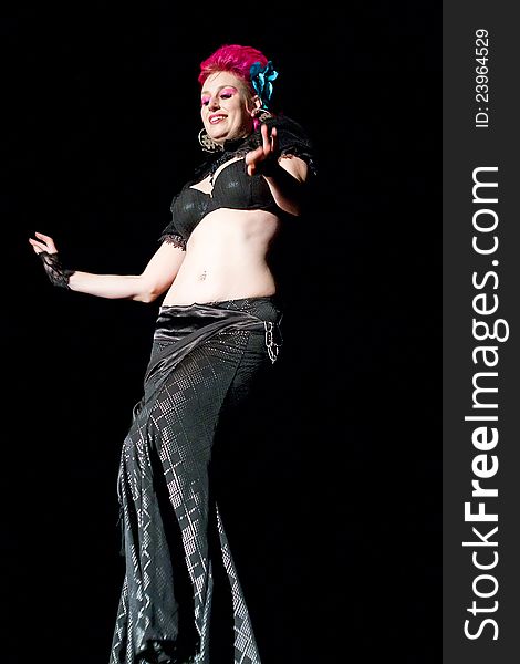 Beautiful red haired belly dancer on black background.