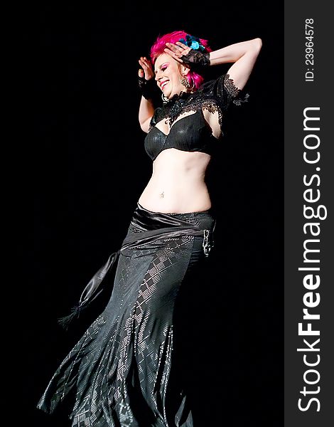 Beautiful red haired belly dancer on black background.