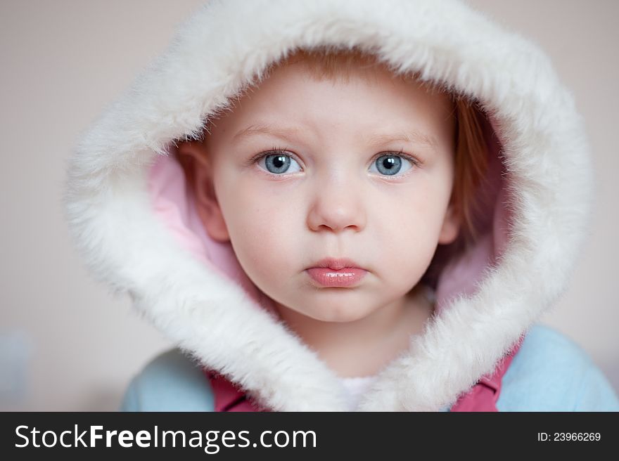 Closeup. Beautiful baby with white hood over gray background. Closeup. Beautiful baby with white hood over gray background