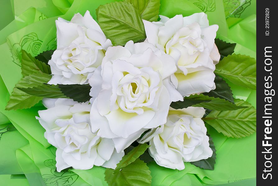Artificial flowers made ??from white plastic with green leaves. Artificial flowers made ??from white plastic with green leaves.