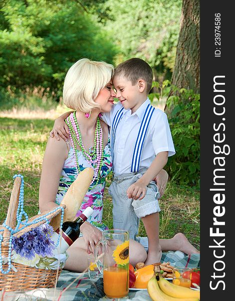 Happy family on a picnic. The son embraces mother.