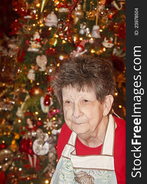 An older woman in front of a Christmas tree. An older woman in front of a Christmas tree