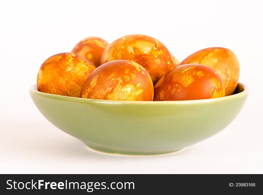 A green bowl holds naturally dyed golden marbled Easter eggs