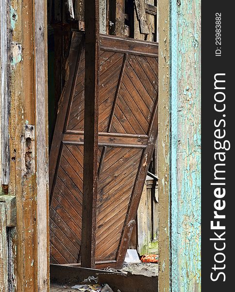 Old broken house entrance detail. Wooden column and damaged door