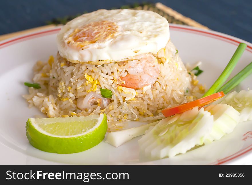 Shrimp fried rice and egg fired put topping on the dish with vegetables.
