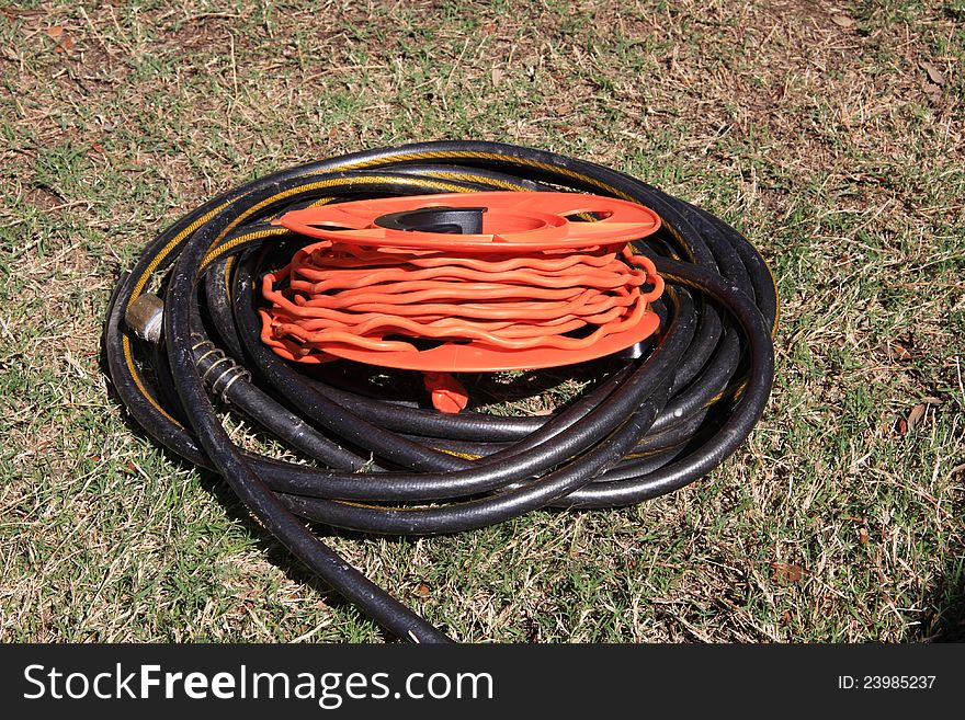 Garden equipment,electric cord and water hose on the grass. Garden equipment,electric cord and water hose on the grass.