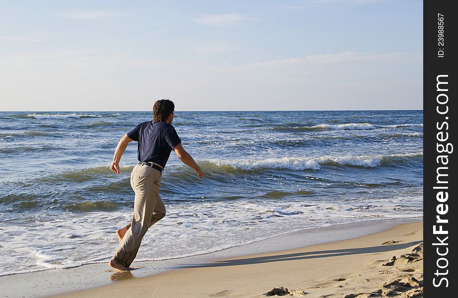 Man running along seashore on a sunny summer day