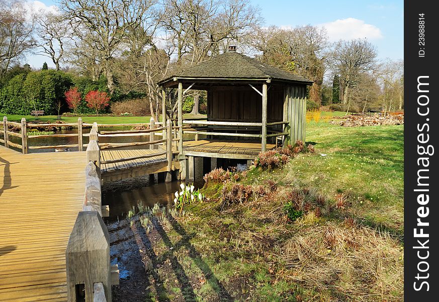 Arrival of Spring in an English park with footbridge and wooden shelter building. Arrival of Spring in an English park with footbridge and wooden shelter building