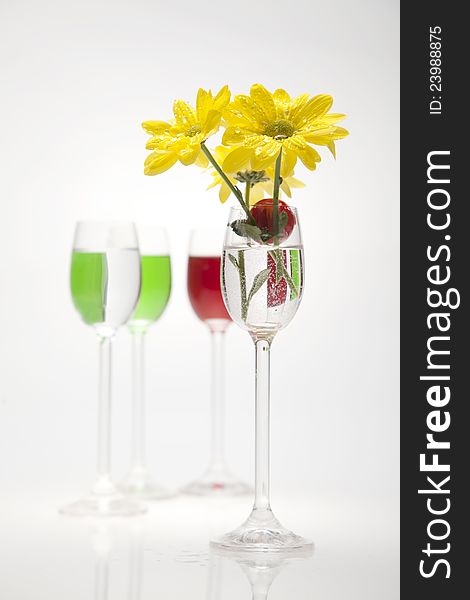 A Glass, Cherry And Yellow Flowers On A White Back