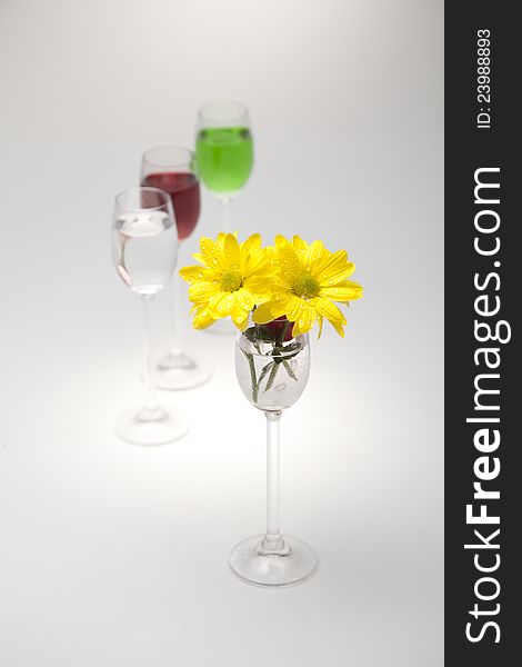 A Glass, Cherry And Yellow Flowers On A White Back