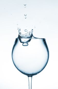 A Glass Of Clear Liquid And A Drop Falling Into It Stock Photos