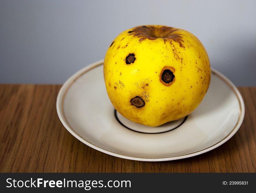 Bright yellow apple on white plate closeup. Bright yellow apple on white plate closeup