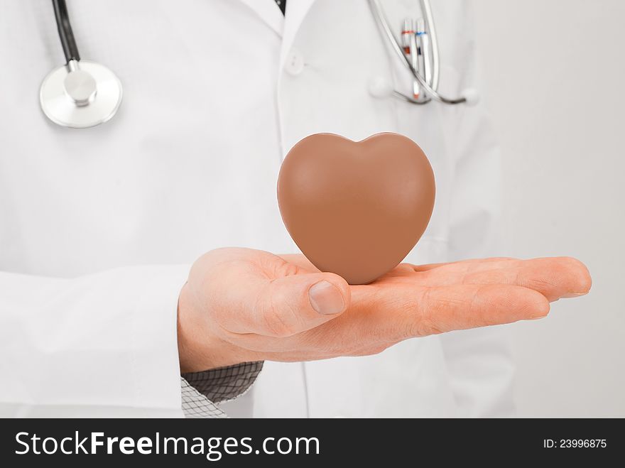 Doctor with stethoscope and chocolate heart on palm - studio shot. Doctor with stethoscope and chocolate heart on palm - studio shot