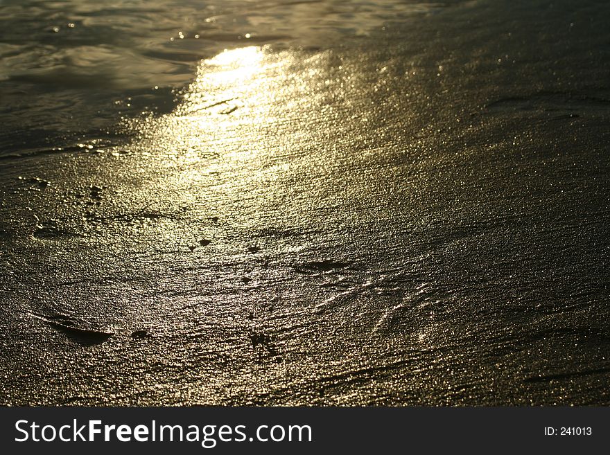 A shot of the reflection of evening light on wet sand of the beach