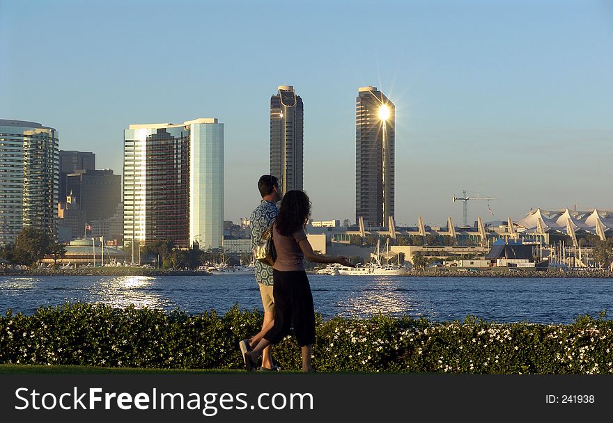 Couple taking a romantic sunset walk on Coronado Island with San Diego skyline background. Couple taking a romantic sunset walk on Coronado Island with San Diego skyline background.