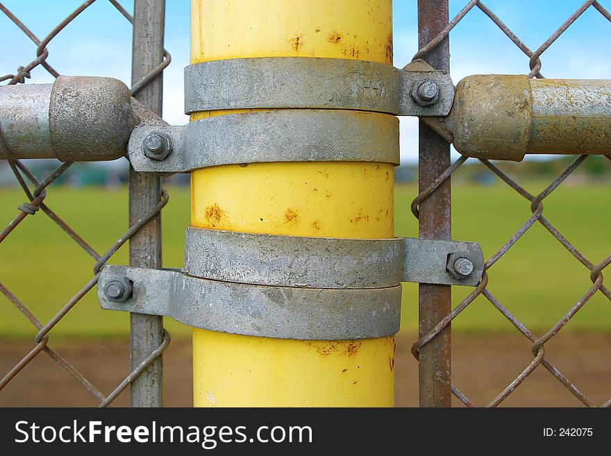 Yellow Metal Rusty old post and fence at a baseball field. Yellow Metal Rusty old post and fence at a baseball field