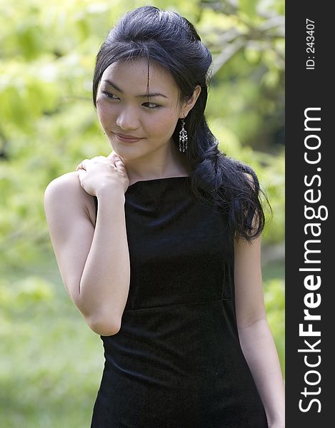 A beautiful asian model in a black evening dress posing outdoors. A beautiful asian model in a black evening dress posing outdoors