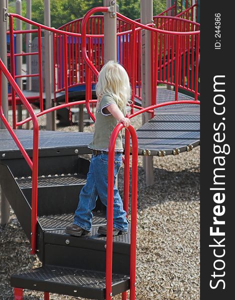 Little girl exploring play area in park,hoping to make a friend. Little girl exploring play area in park,hoping to make a friend