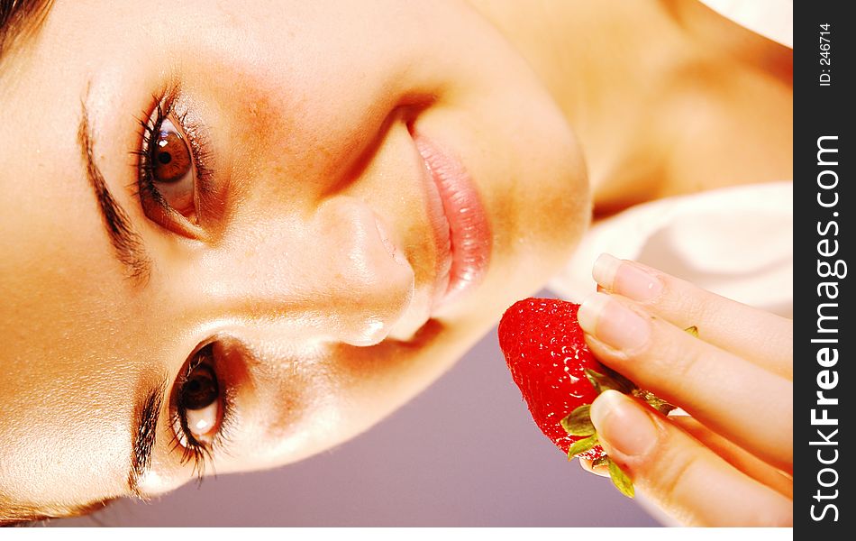 Attractive girl enjoying a refreshing, tasty strawberry. Attractive girl enjoying a refreshing, tasty strawberry