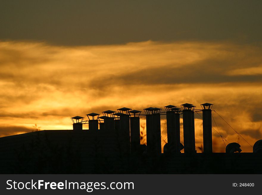 Vent stacks silhouetted against a sunset. Vent stacks silhouetted against a sunset.