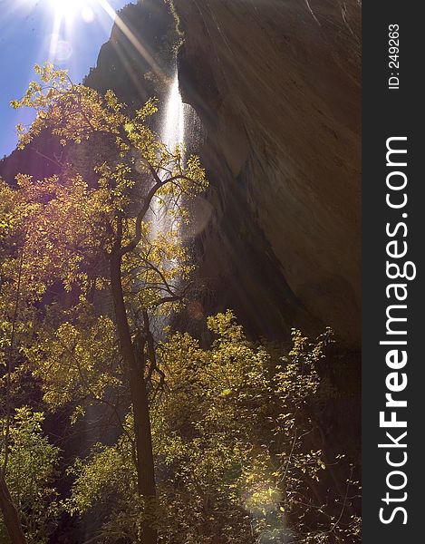 A waterfall in the middle of a canyon, with the sun shining bright up above. A waterfall in the middle of a canyon, with the sun shining bright up above