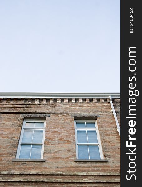 Two vertical windows on a brick building with blue sky and copy space. Two vertical windows on a brick building with blue sky and copy space.